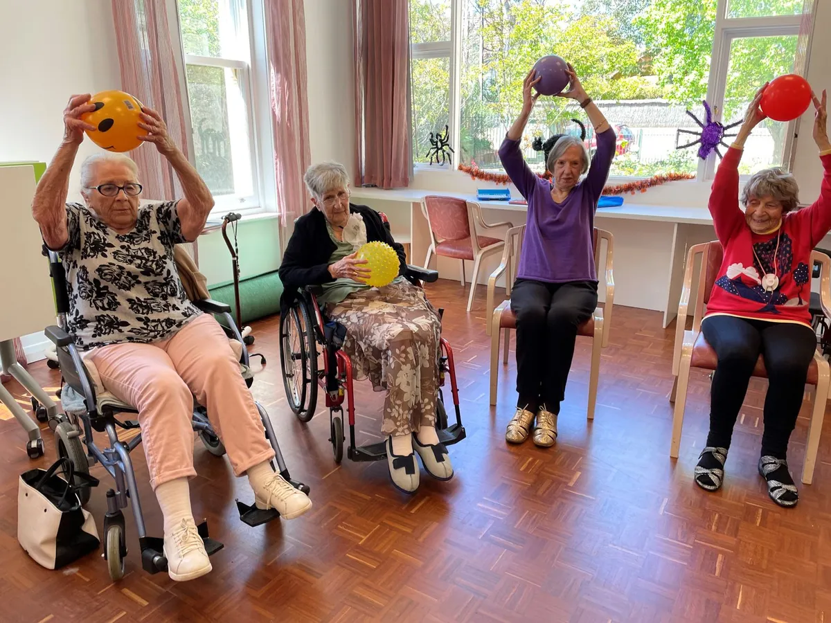 Older adults in a seated exercise class using colorful balls for activity.