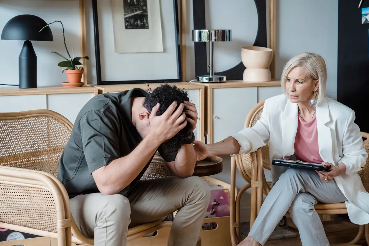Therapist comforting a patient with head in hands during a session.