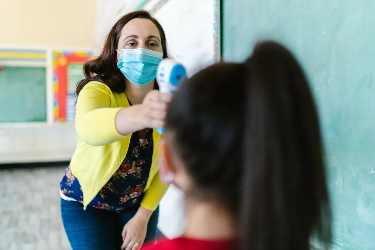 School nurse checking a student’s temperature with a thermometer.