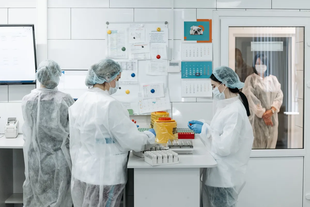 Laboratory staff in protective gear working with samples and equipment.