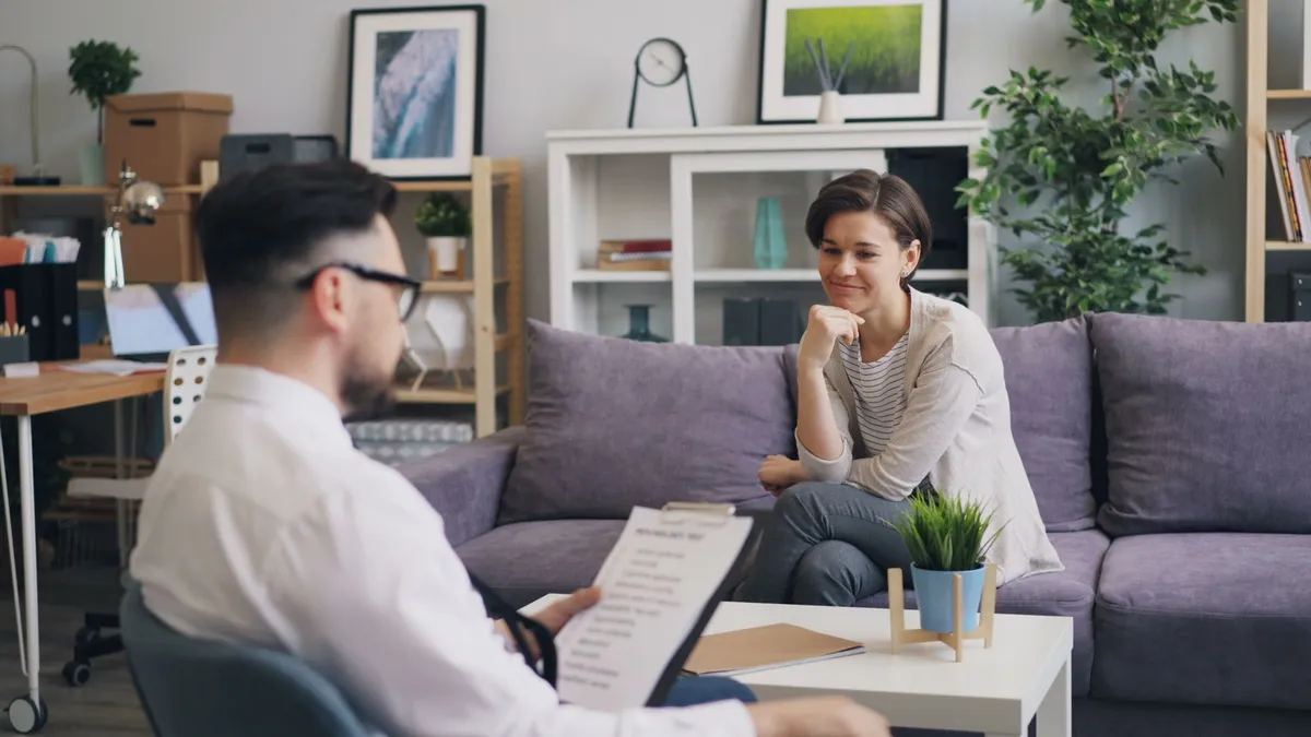 A therapist and client engaged in conversation in a cozy therapy office.