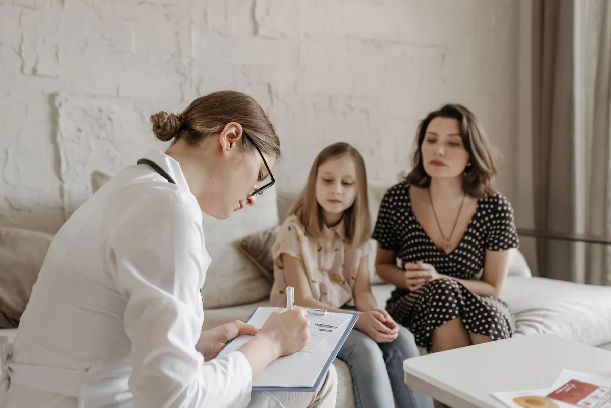 Pediatrician consulting with a mother and her daughter in a cozy office setting.