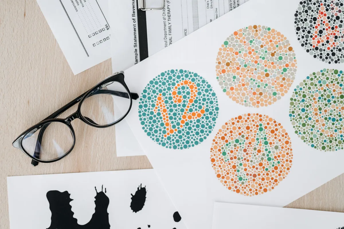 Color vision test charts with numbers visible among colored dots and glasses nearby.