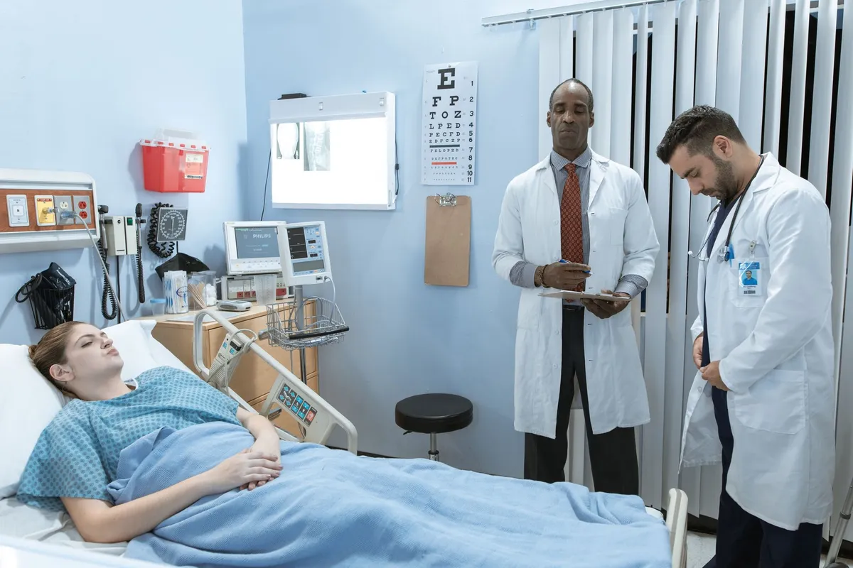 Doctor and nurse attending to a patient in a hospital room.