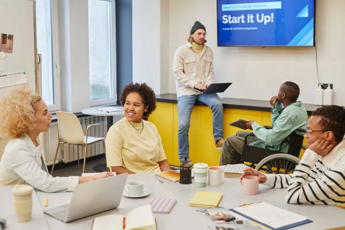 A diverse group discussing in a meeting room with a presentation screen.