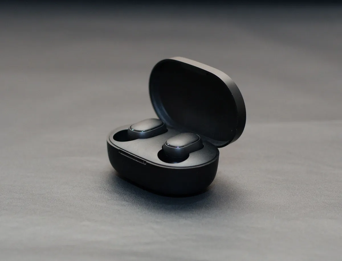 Close-up of wireless earbuds in a case on a dark background.