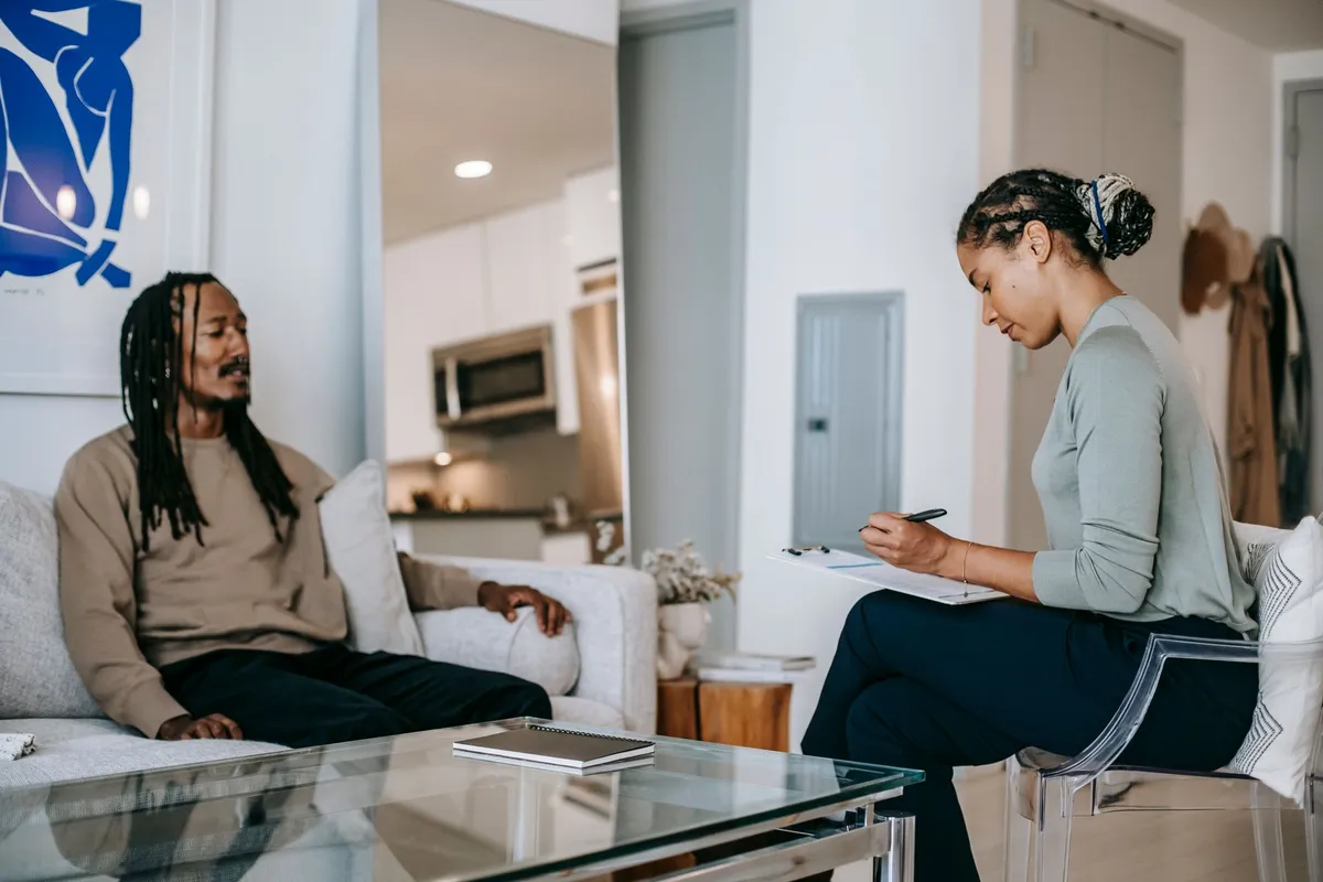 A therapist and a man engaged in a counseling session in a modern living room.