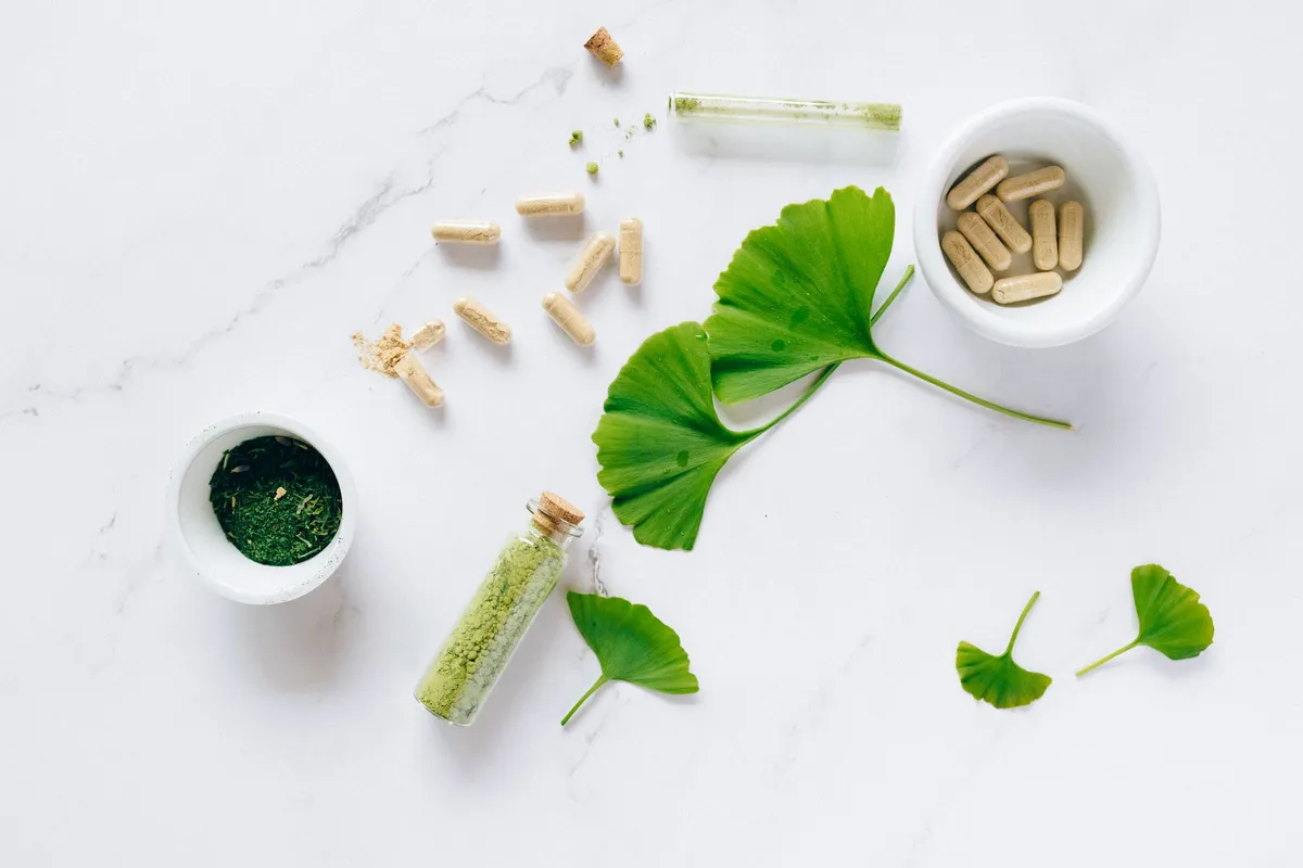 Various complementary medicine products including herbs and capsules on a marble surface.