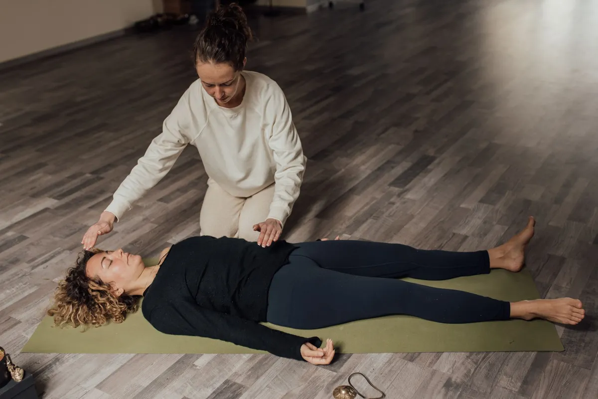 Practitioner performing a healing technique on a client lying on a yoga mat