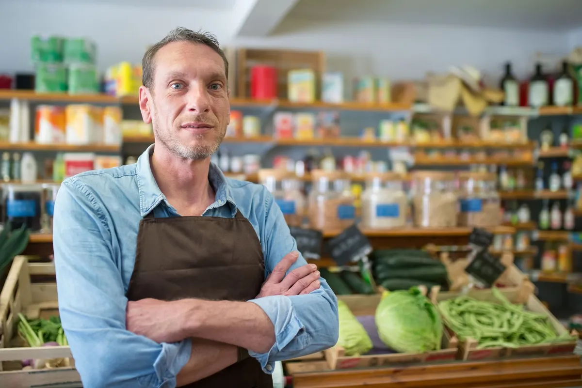 Man standing in a health food store with shelves of products behind him.