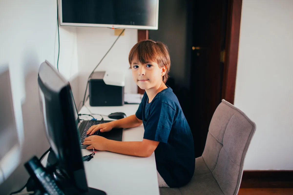 Child sitting at a desk using a computer with proper posture.