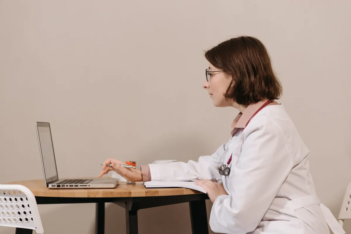 Female doctor reviewing patient information on a laptop at a table.