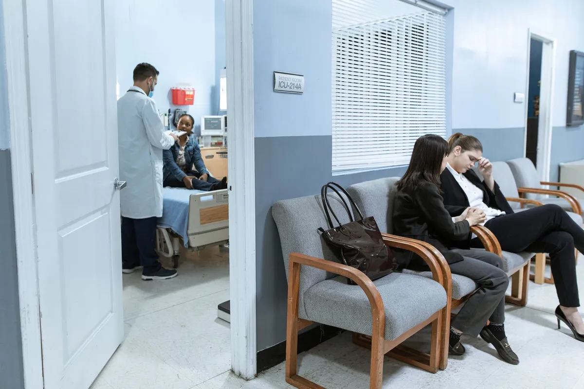 Patients waiting in a healthcare facility with a doctor attending to another patient.