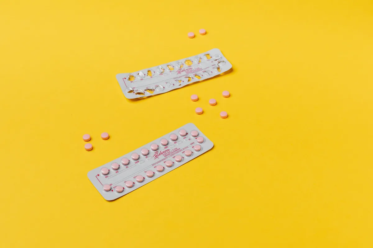 Two packs of birth control pills on a yellow background.