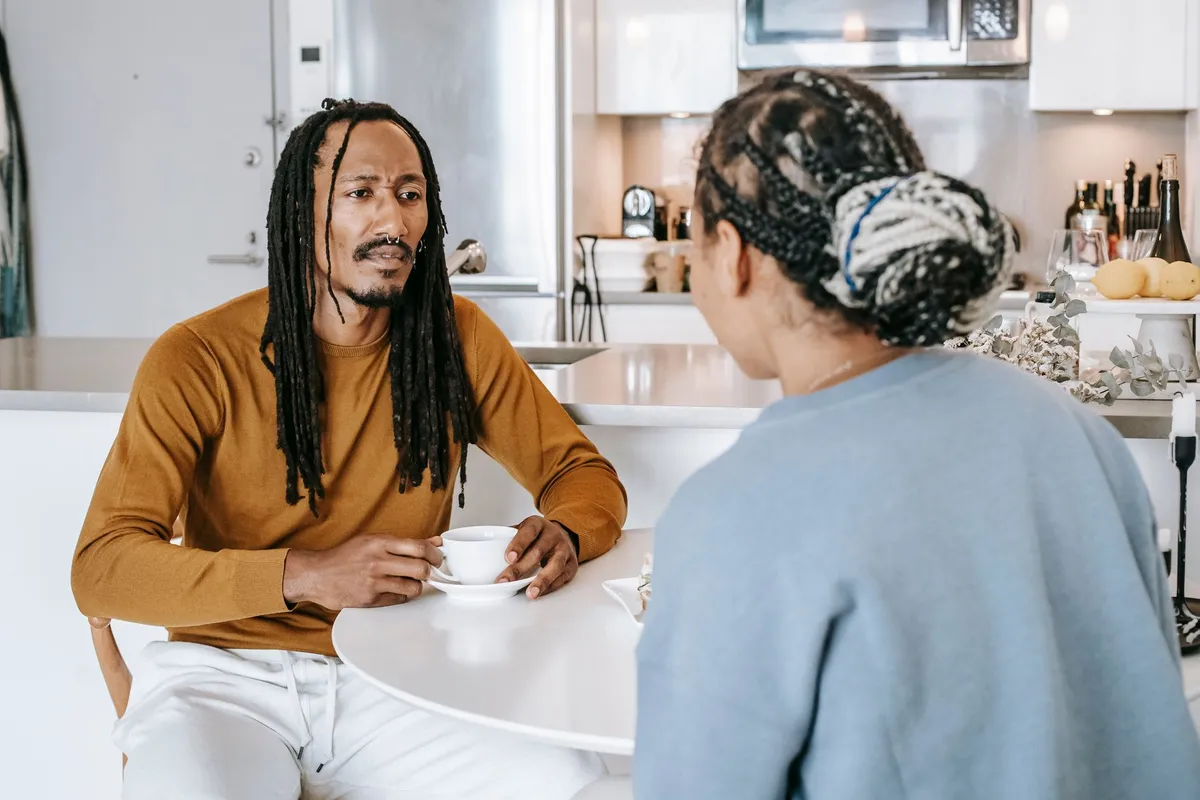 Couple discussing at a table with coffee, focusing on a serious conversation.
