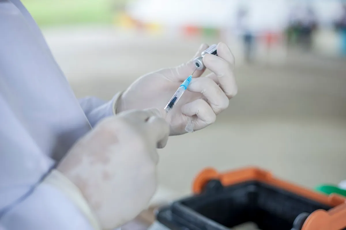 Healthcare provider preparing a syringe with a blue liquid for injection.