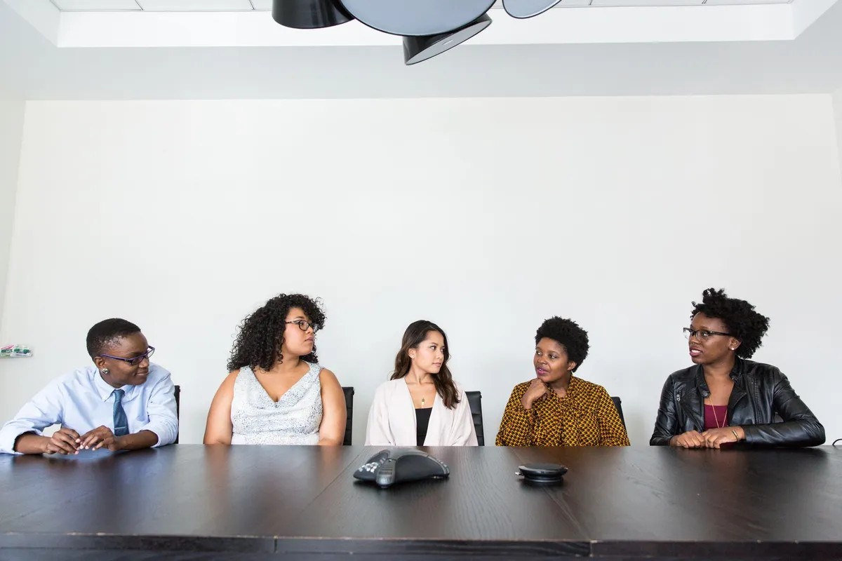 Five women seated at a table discussing topics, possibly including contraception options.