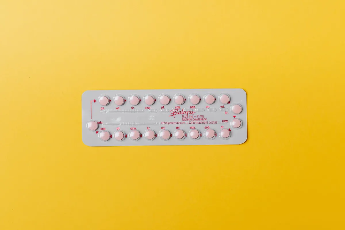 Blister pack of combined oral contraceptive pills on a yellow background.