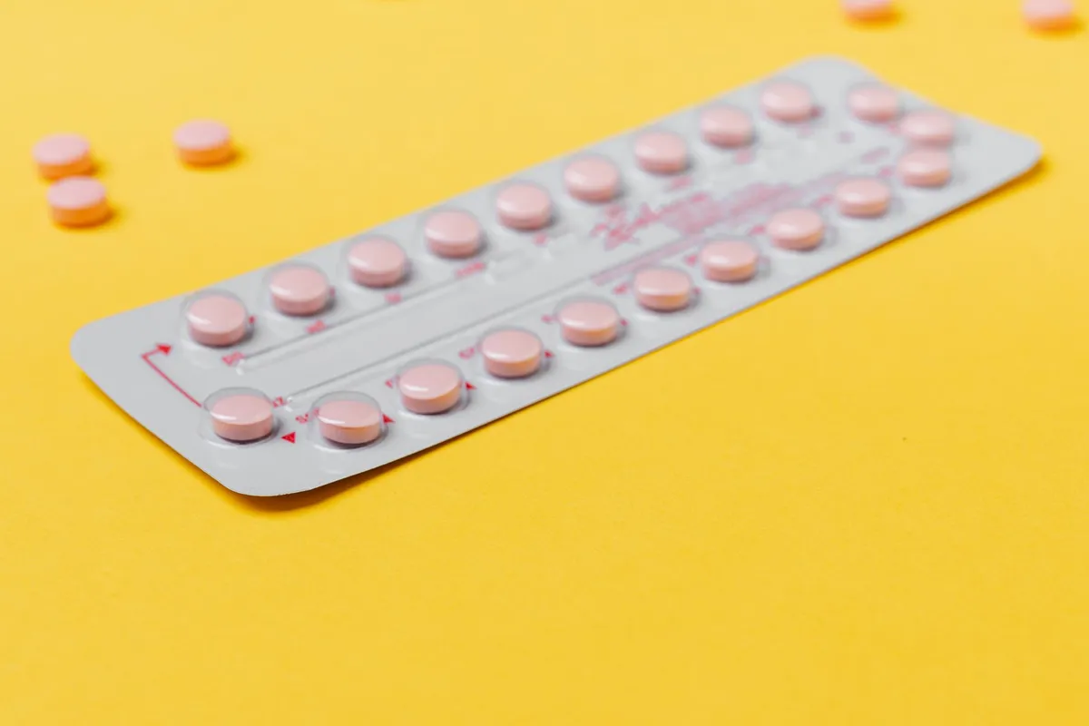 Pink birth control pills on a yellow background, representing hormonal contraception.