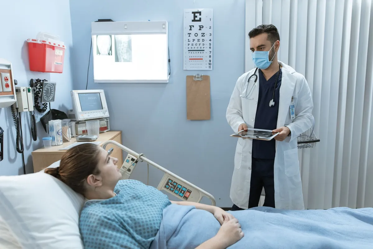 Healthcare professional discussing recovery with a patient in a hospital room.