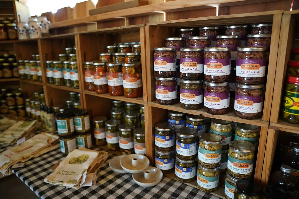Shelves filled with jars of preserved vegetables and fruits in a kitchen setting.