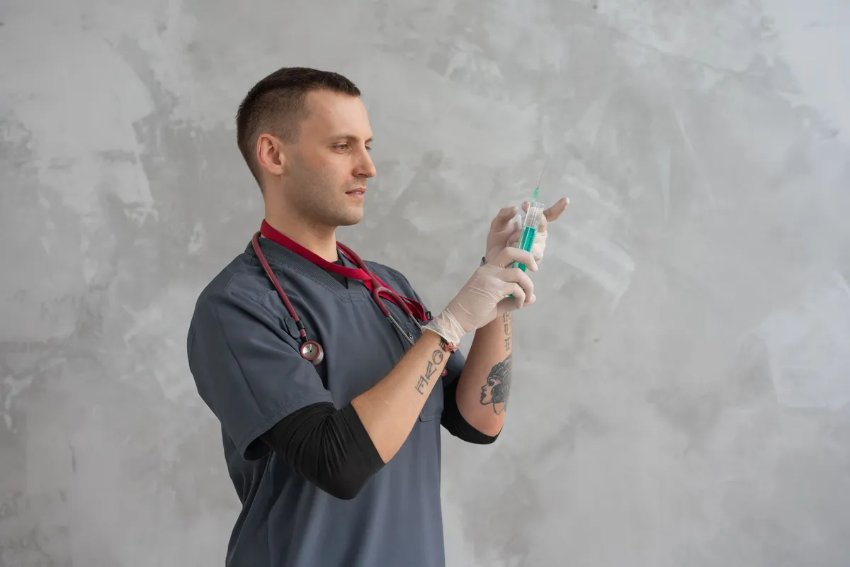 Healthcare professional preparing an injectable syringe in a clinical setting.