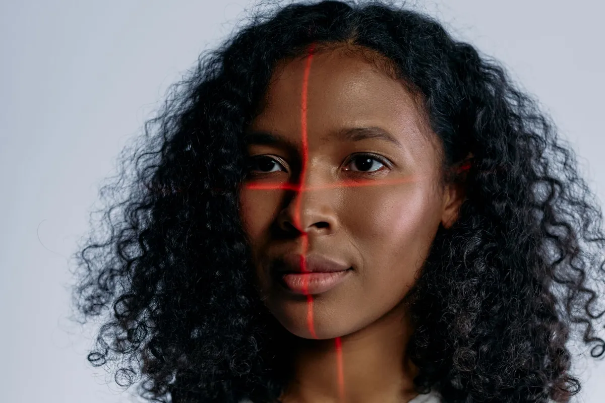 Close-up of a woman’s face with a red grid overlay for cosmetic treatment analysis.