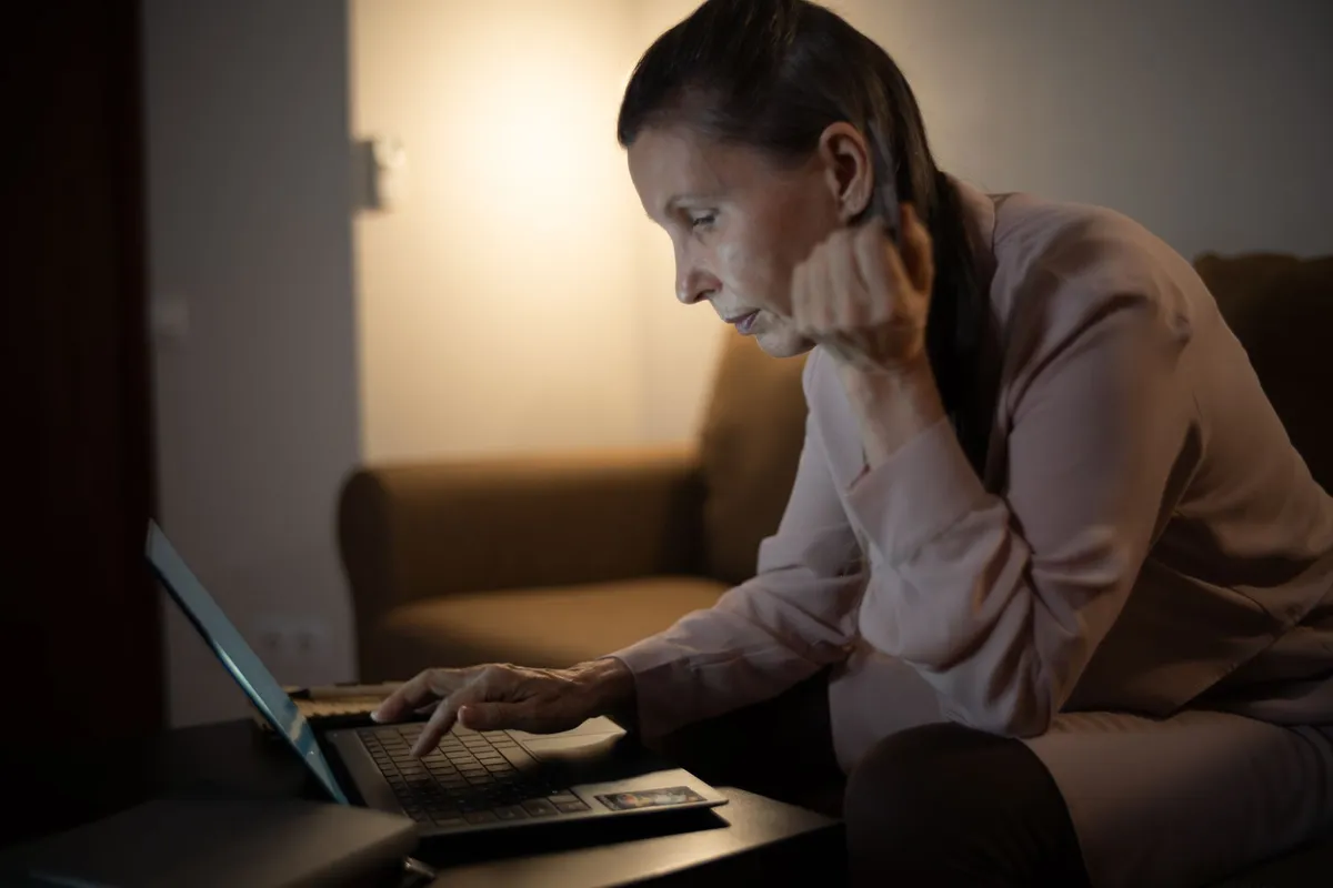 Woman engaged in online counseling at night with a laptop.