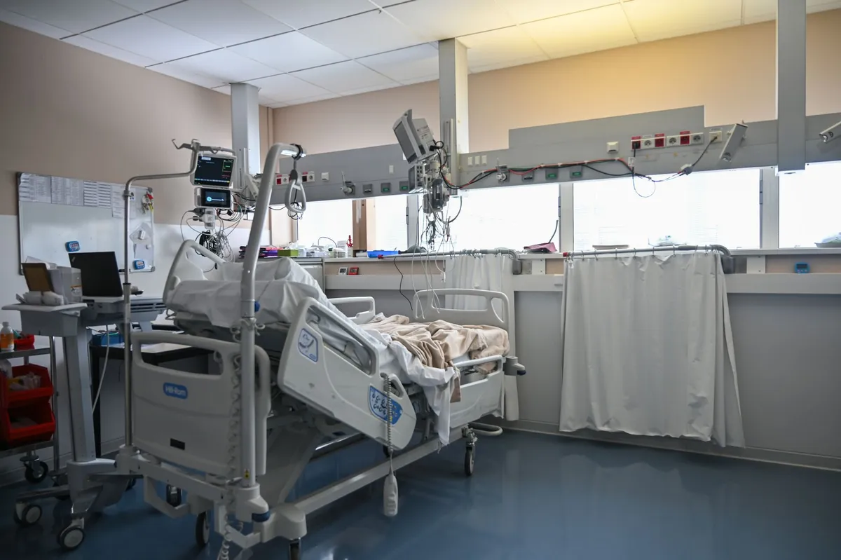 Hospital room with an empty patient bed and medical equipment visible.