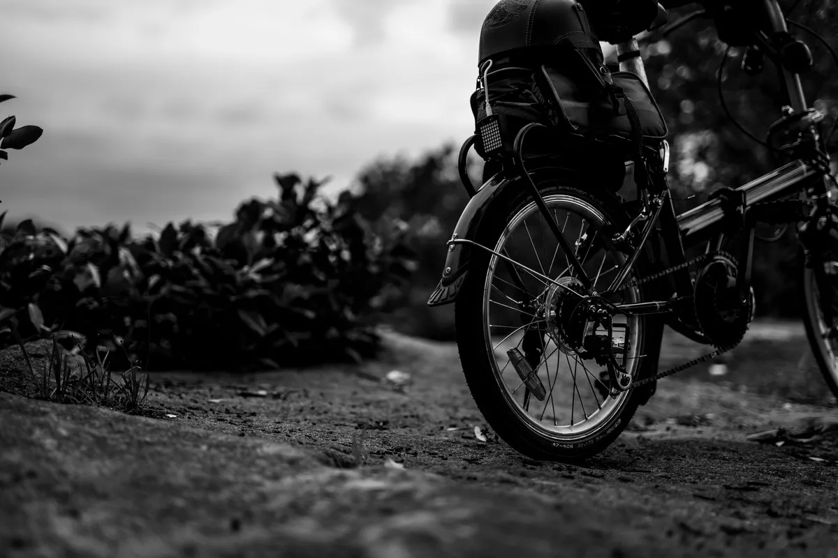 Close-up of a bicycle wheel on a dirt path, illustrating cycling as exercise.