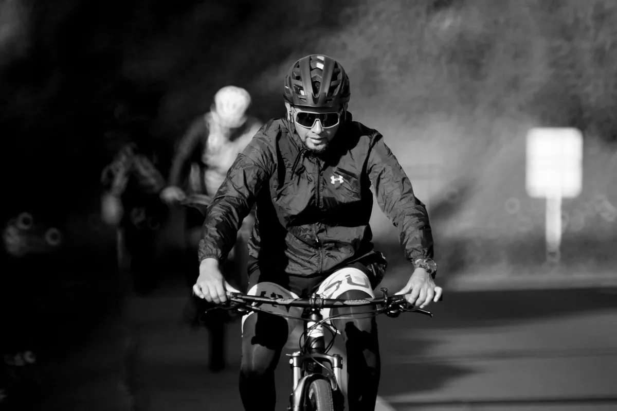 Cyclist wearing a helmet riding on a road, demonstrating safe cycling practices.