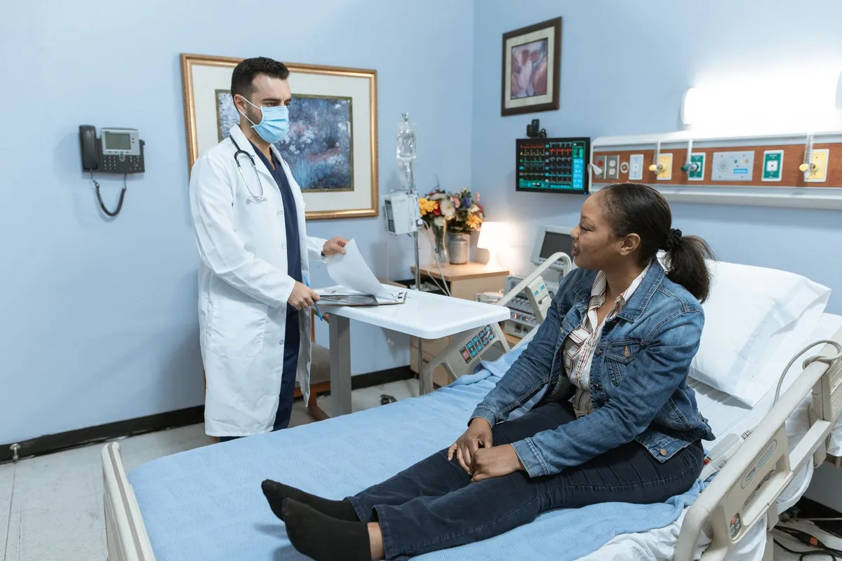 Doctor in a mask consulting with a female patient in a medical office.