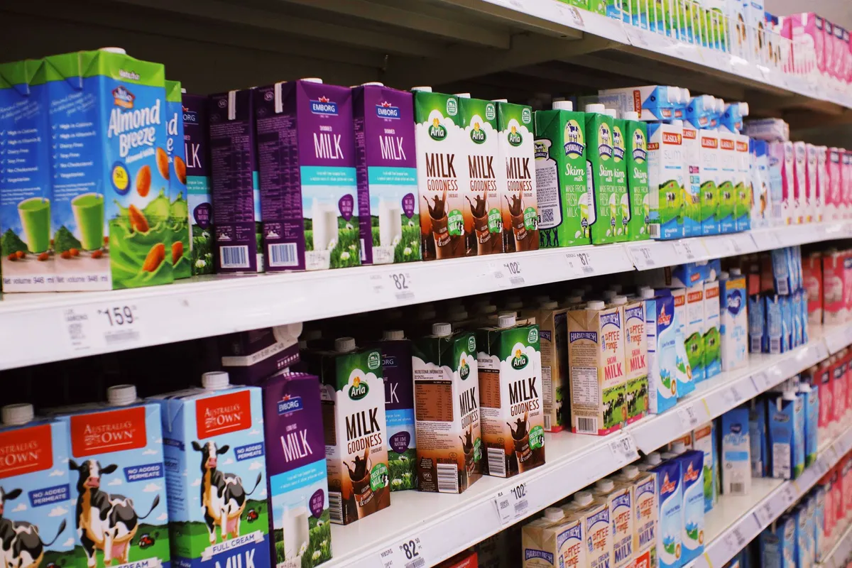 Shelves stocked with various dairy and dairy alternative products in a grocery store.