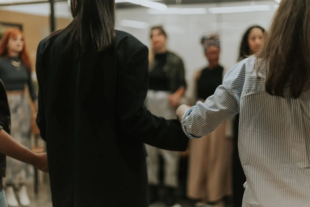 Women holding hands in a supportive group setting.