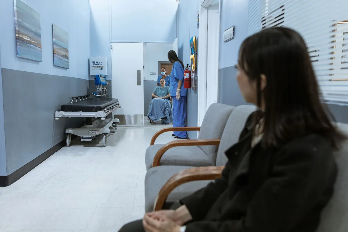 A hospital waiting room with a patient and medical staff in view.