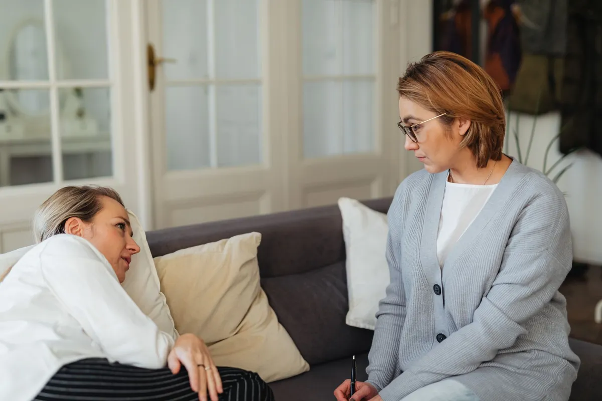 Therapist listening to an elderly client discussing feelings on a couch.
