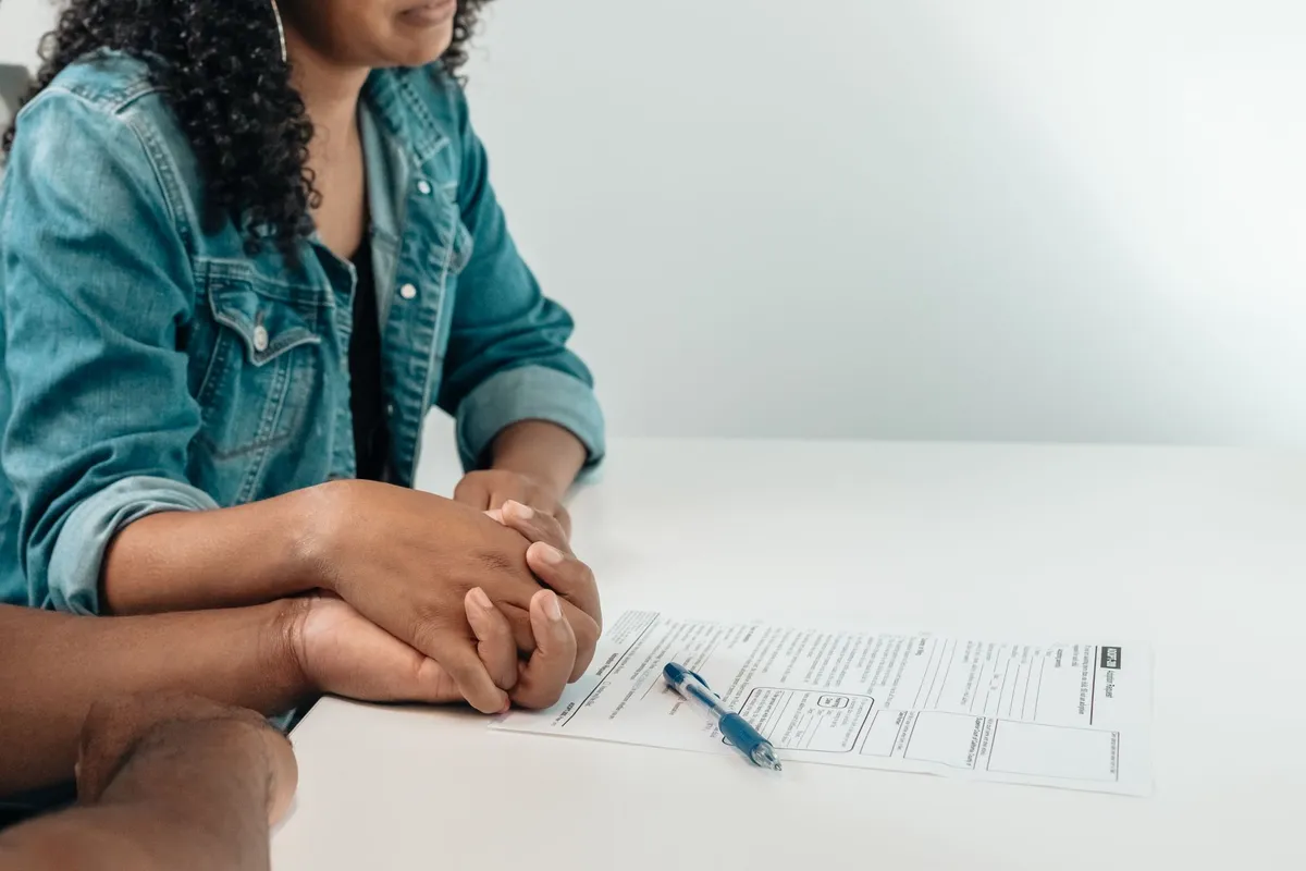 Two hands holding each other over a medical form on a table.