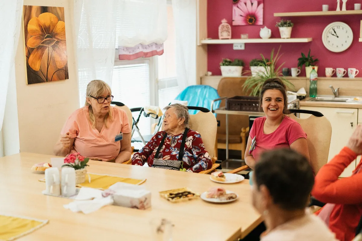 Caregivers and seniors engaged in conversation during a group meeting in a supportive environment.