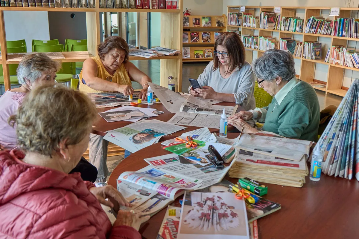 Seniors engaged in a craft activity at a table with newspapers and supplies.