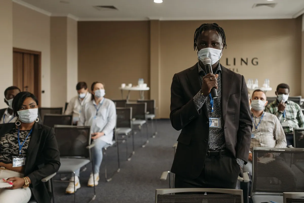 Person speaking at a community health workshop with attendees wearing masks.